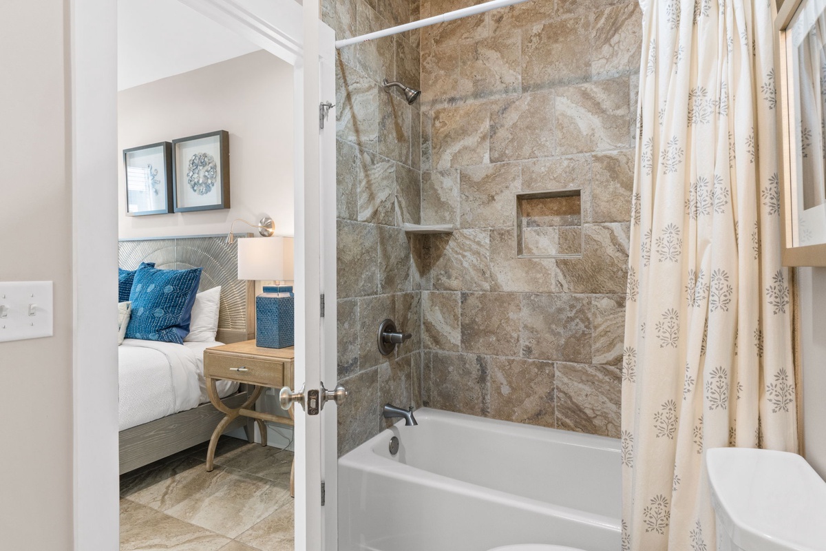 Unwind in your private bathroom featuring a soaking tub and rainfall shower, wrapped in elegant stone tilework and thoughtful touches that make every stay feel special.