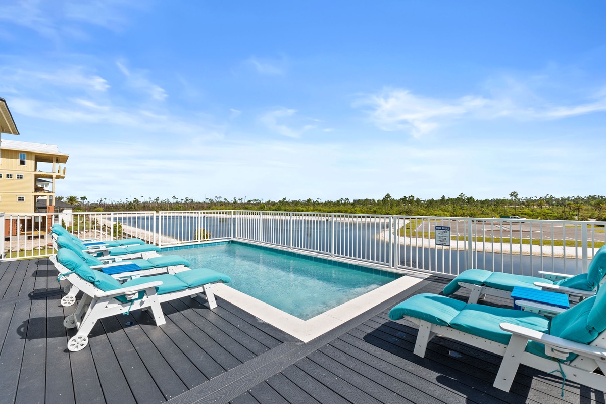 Rooftop deck with small pool and lounge chairs overlooking expansive wetlands under clear skies, providing scenic outdoor relaxation near the property.
