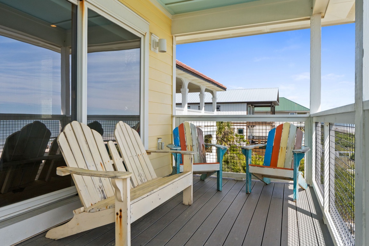 Unwind on your private balcony with colorful Adirondack chairs and ocean views, perfect for morning coffee or sunset relaxation.