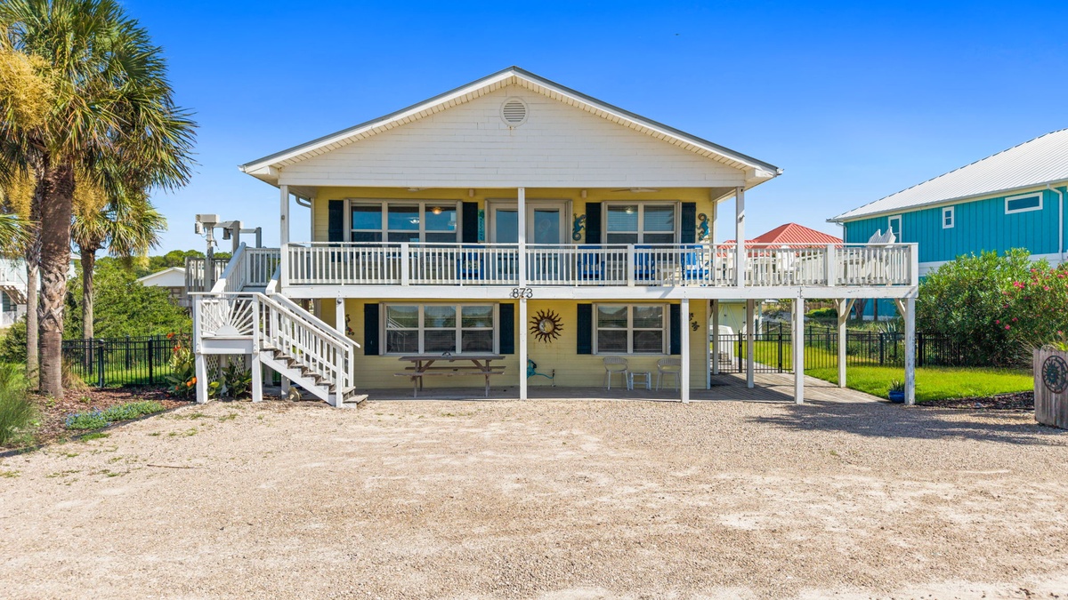 This cheerful coastal home welcomes you with its classic beach-house charm, featuring a spacious wrap-around porch, elevated design, and relaxed island vibe—your perfect home base for sun-soaked adventures.