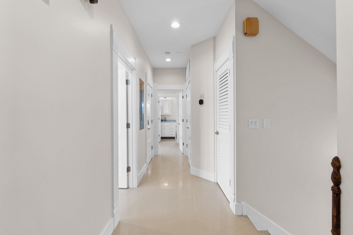 Walk through your bright, modern hallway with gleaming floors and fresh white walls leading to comfortable bedrooms and bathrooms.