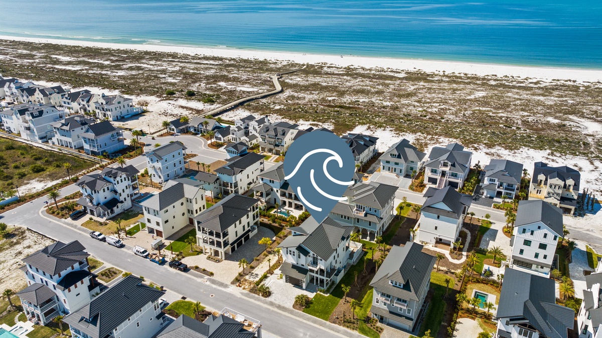 Aerial perspective of a beachfront residential community featuring modern coastal architecture, pristine white sand, and direct access to turquoise Gulf waters.