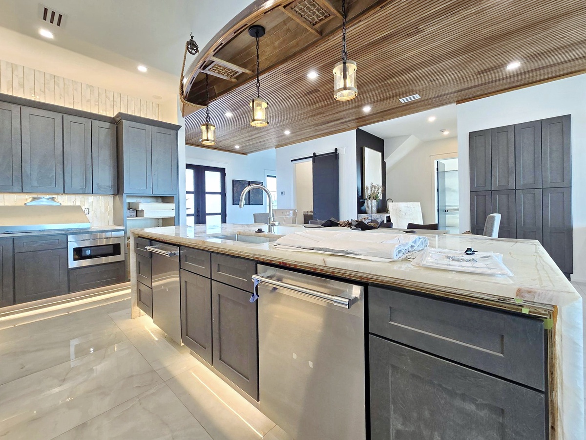 Your gourmet kitchen awaits with marble countertops, premium appliances, and stunning wood beam ceiling—perfect for creating memorable meals together.