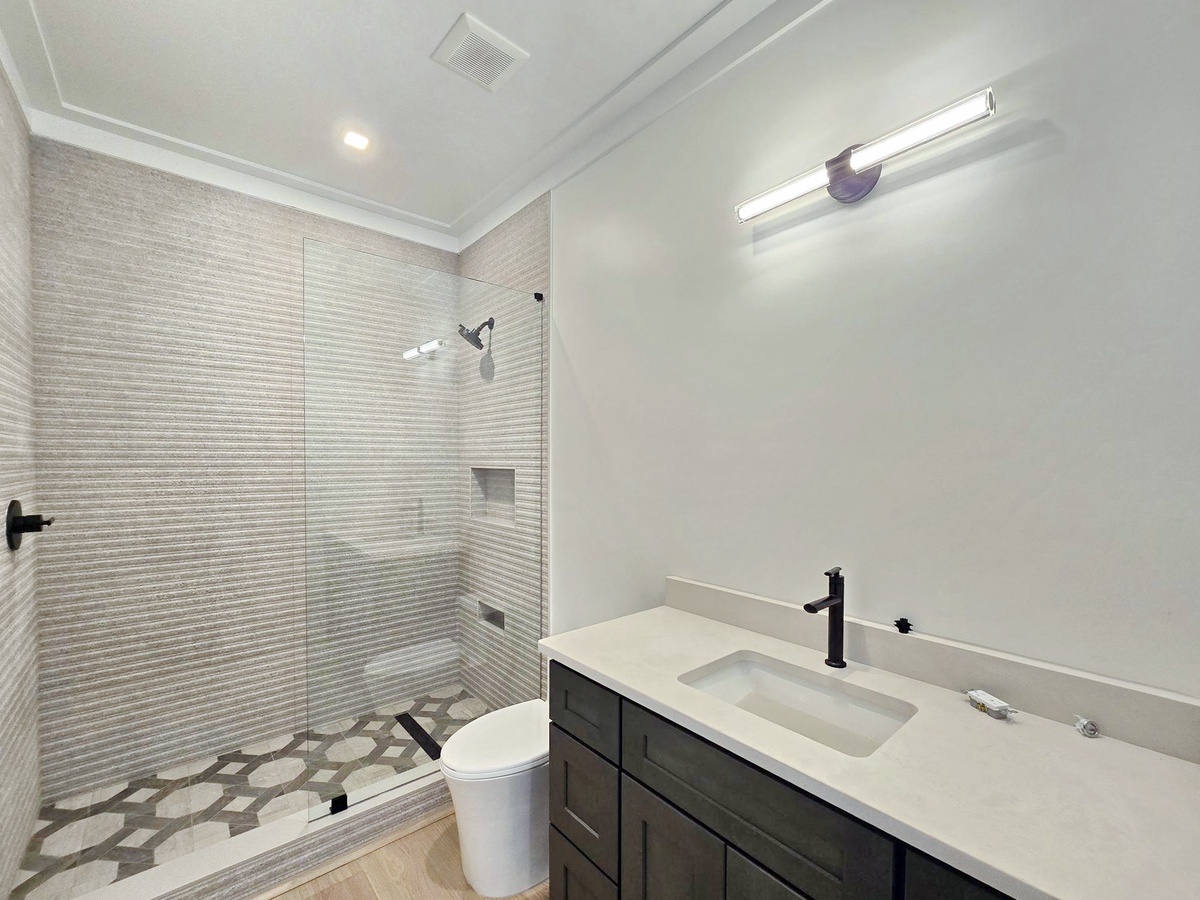 Step into your private spa-like bathroom featuring elegant tile work, modern fixtures, and a spacious glass-enclosed shower for pure relaxation.