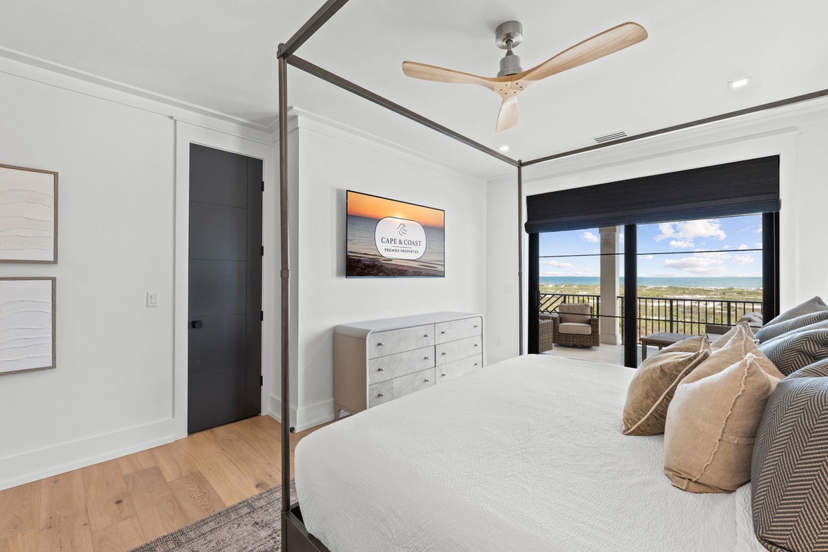 Picture yourself waking up in this serene bedroom with sweeping coastal views through floor-to-ceiling glass doors. The plush bed, ceiling fan, and direct balcony access create your perfect seaside retreat.