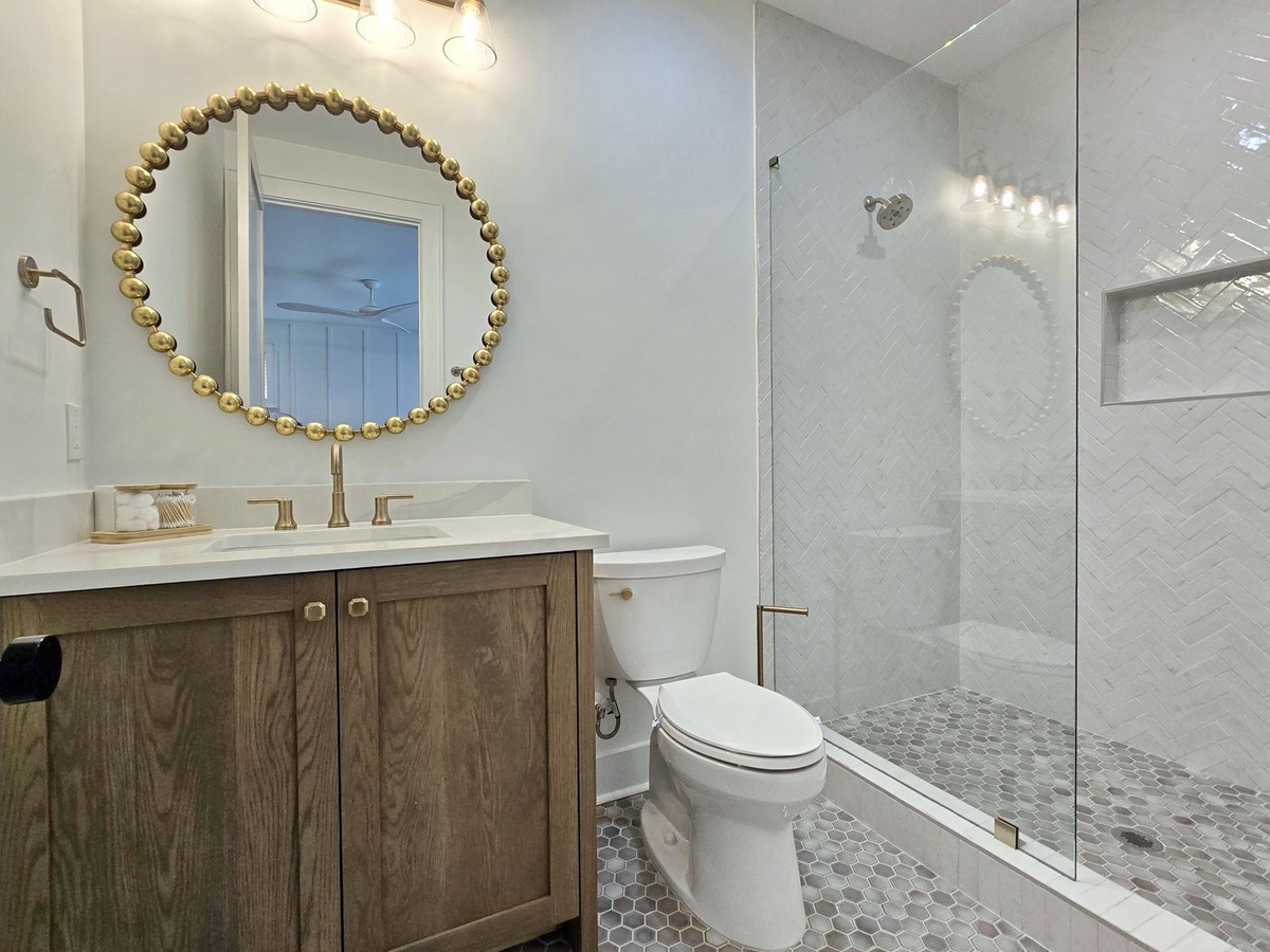 Refresh in your elegant ensuite with its stunning gold-beaded mirror, marble vanity, and spacious glass shower featuring gorgeous herringbone tile.
