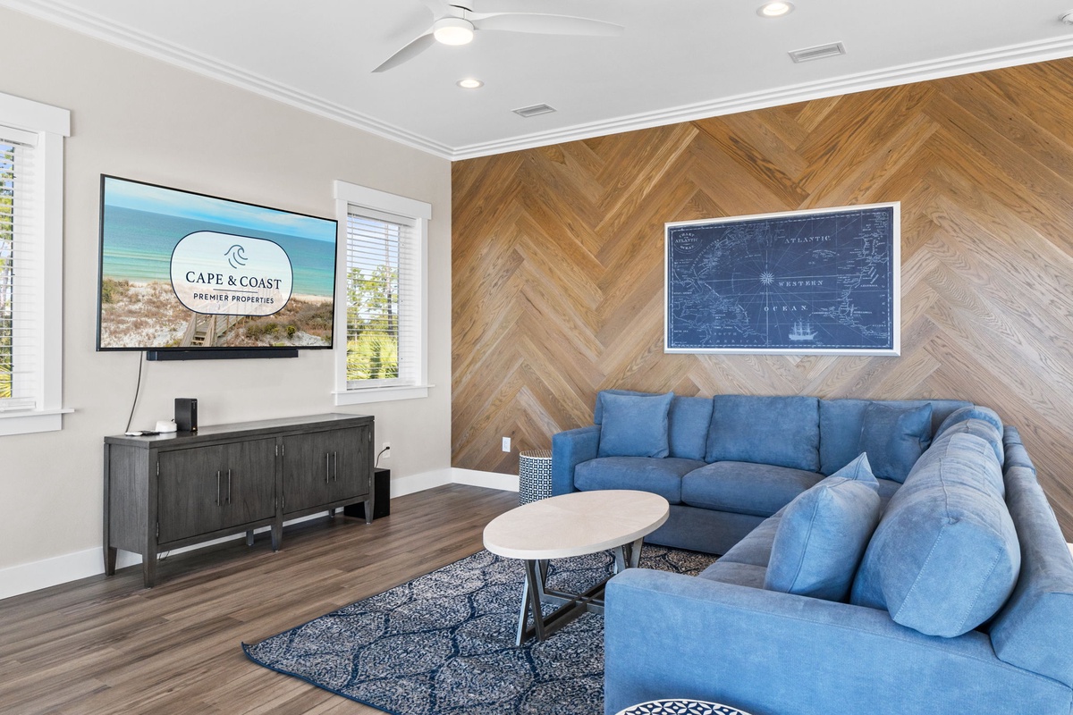 Sink into plush blue sectional seating where you can unwind with your favorite shows on the large TV in this stylish coastal retreat.