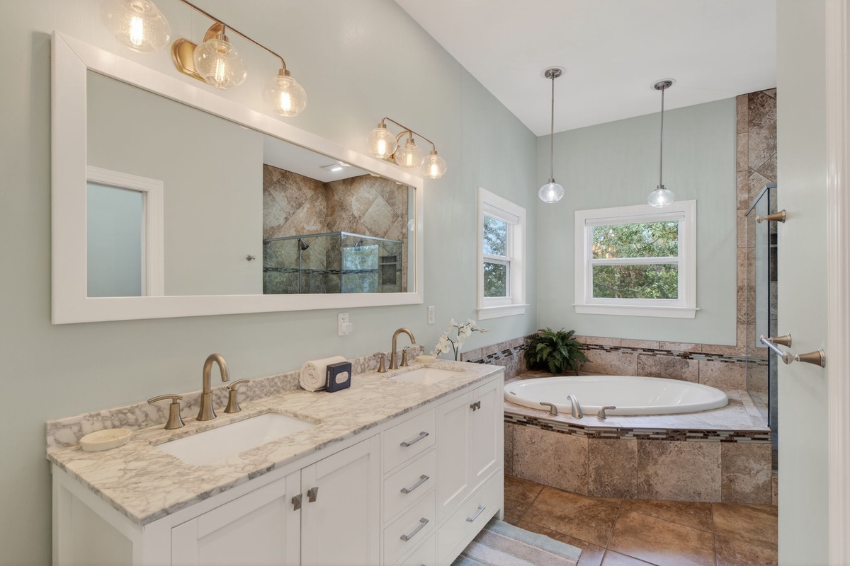 Relax in your spa-like bathroom with a soaking tub, marble vanity, and elegant lighting.