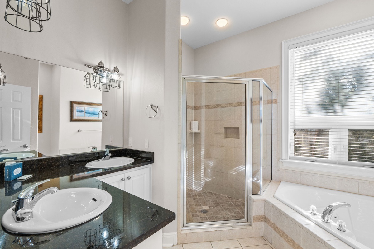 Unwind in your spacious bathroom featuring dual sinks, a relaxing soaking tub, and a separate glass shower.