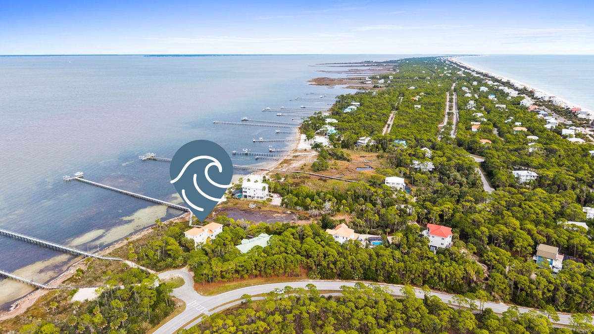 Aerial view of a coastal peninsula community with waterfront homes, piers, and lush vegetation extending into calm waters.