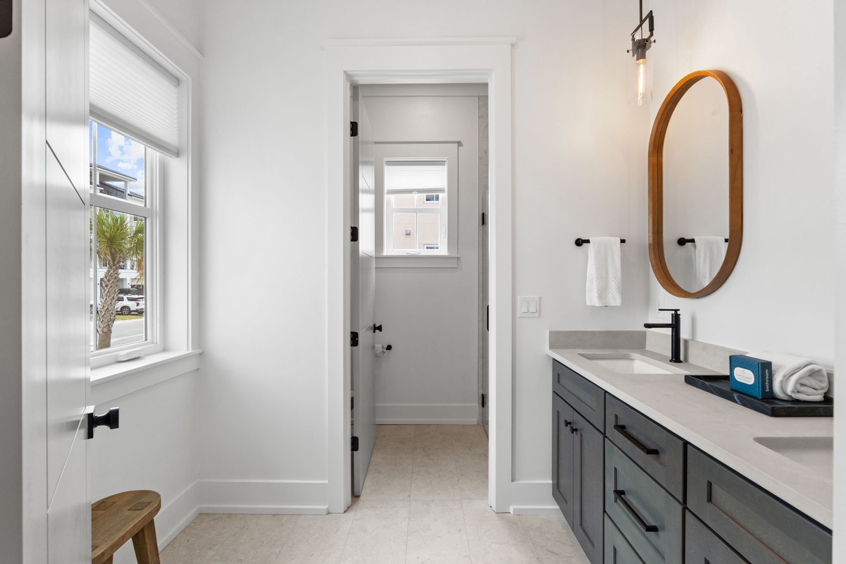 Your stylish bathroom features modern fixtures, an elegant oval mirror, and a spacious vanity perfect for your morning routine.
