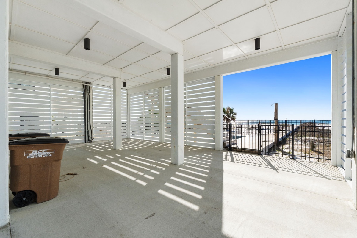 Covered outdoor terrace with ocean views and natural light filtering through white slats.