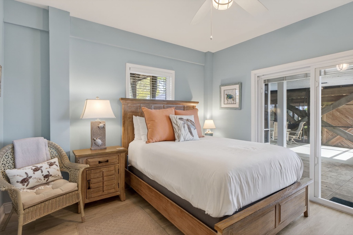 Drift off in your serene coastal bedroom with calming blue walls, cozy reading chair, and French doors opening to your private deck.