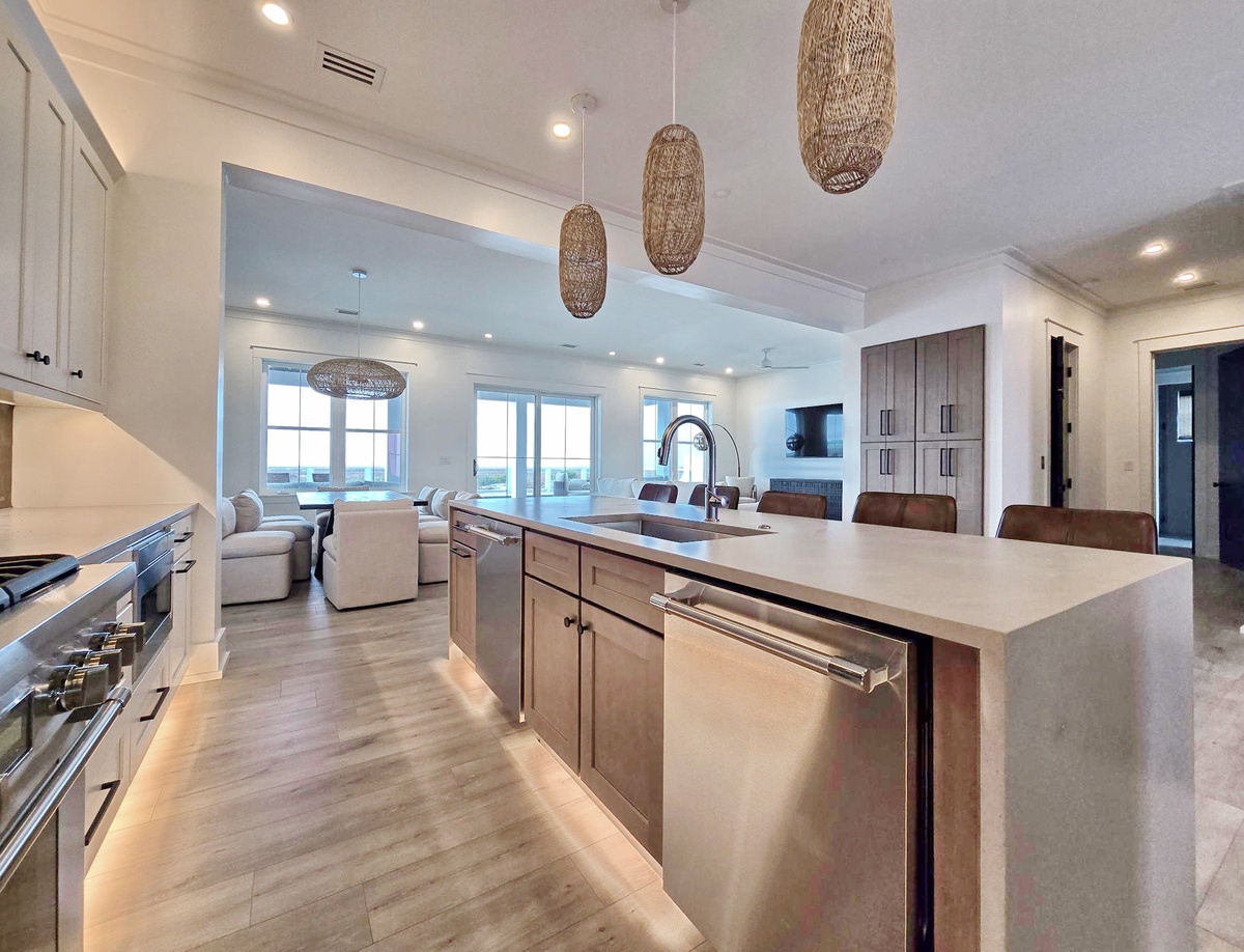 Your spacious open kitchen flows into a bright living area, where modern amenities meet coastal charm beneath stunning woven pendant lights.