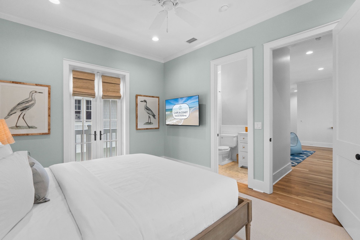 Unwind in this serene bedroom with soft coastal colors, crisp linens, and charming bird artwork. Your private bathroom awaits just steps away, while French doors invite natural light.