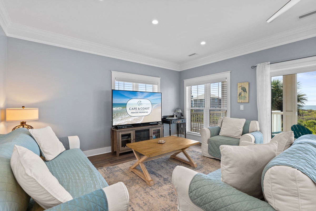 Unwind in your coastal-inspired living room with plush seating, ocean views through multiple windows, and everything you need for relaxation.