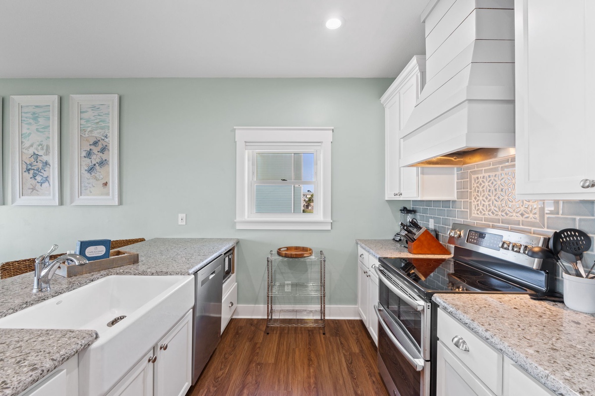 Step into this bright kitchen where coastal charm meets modern convenience. White cabinetry, granite counters, and ocean-inspired artwork create your perfect home-away-from-home cooking space.