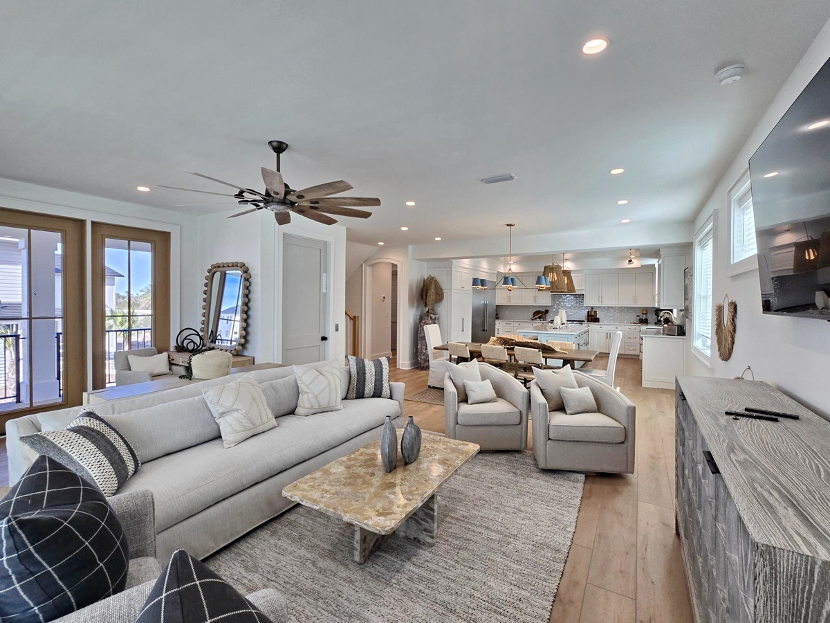 Relax in your spacious open-concept living area with plush seating, modern kitchen, and balcony access for the perfect vacation retreat.