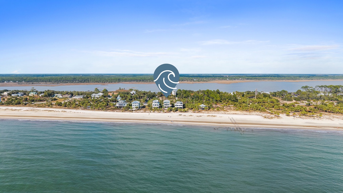 Stunning aerial view captures the pristine beachfront location with crystal-clear waters and sandy shores stretching along the coastline.