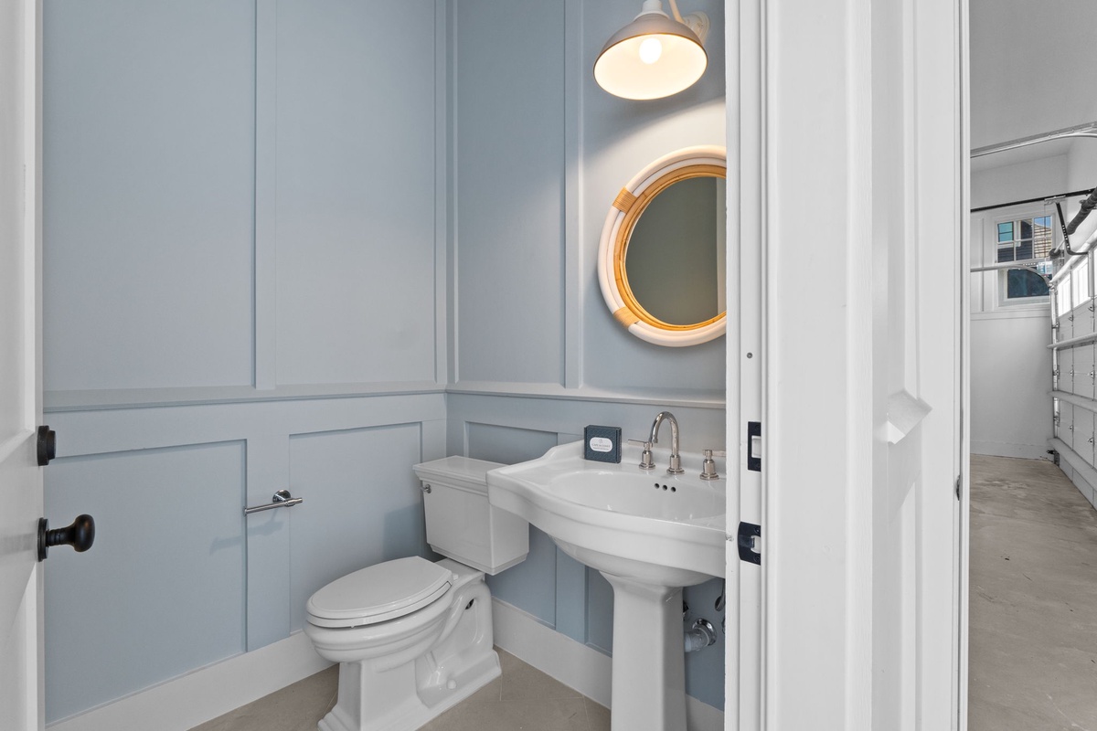 Freshen up in this elegantly designed bathroom with soft blue paneling, a pedestal sink, and warm pendant lighting that creates a soothing retreat.