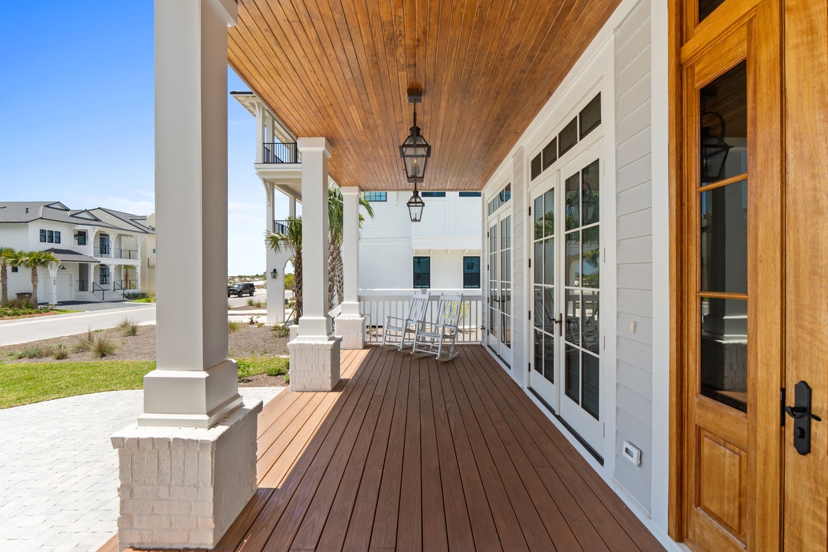 Relax in your porch swing beneath warm wood ceilings and elegant lantern lighting. Step through French doors to discover your coastal retreat framed by swaying palms.