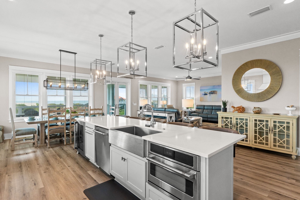 Step into your coastal getaway where the kitchen flows seamlessly into the living space. Modern pendant lighting and a spacious island invite you to gather, cook, and unwind while enjoying sweeping ocean views through expansive windows.