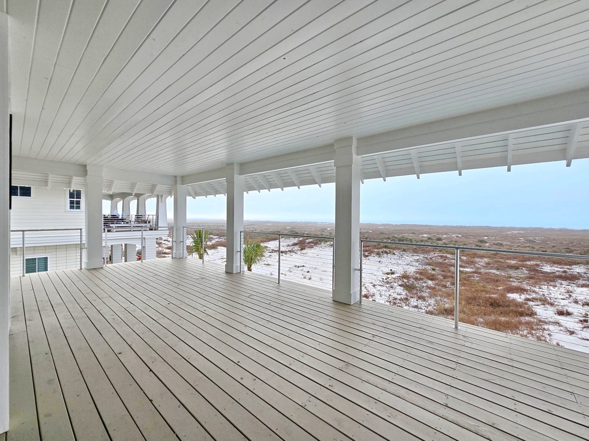 Relax on your private covered terrace overlooking pristine coastal dunes, where endless views stretch to the horizon.