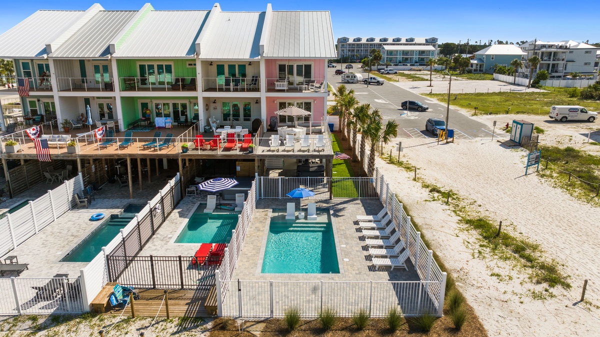 Aerial view showcasing the colorful beachside property with inviting pools, spacious patios, and direct beach access, nestled in a vibrant coastal neighborhood perfect for your getaway.