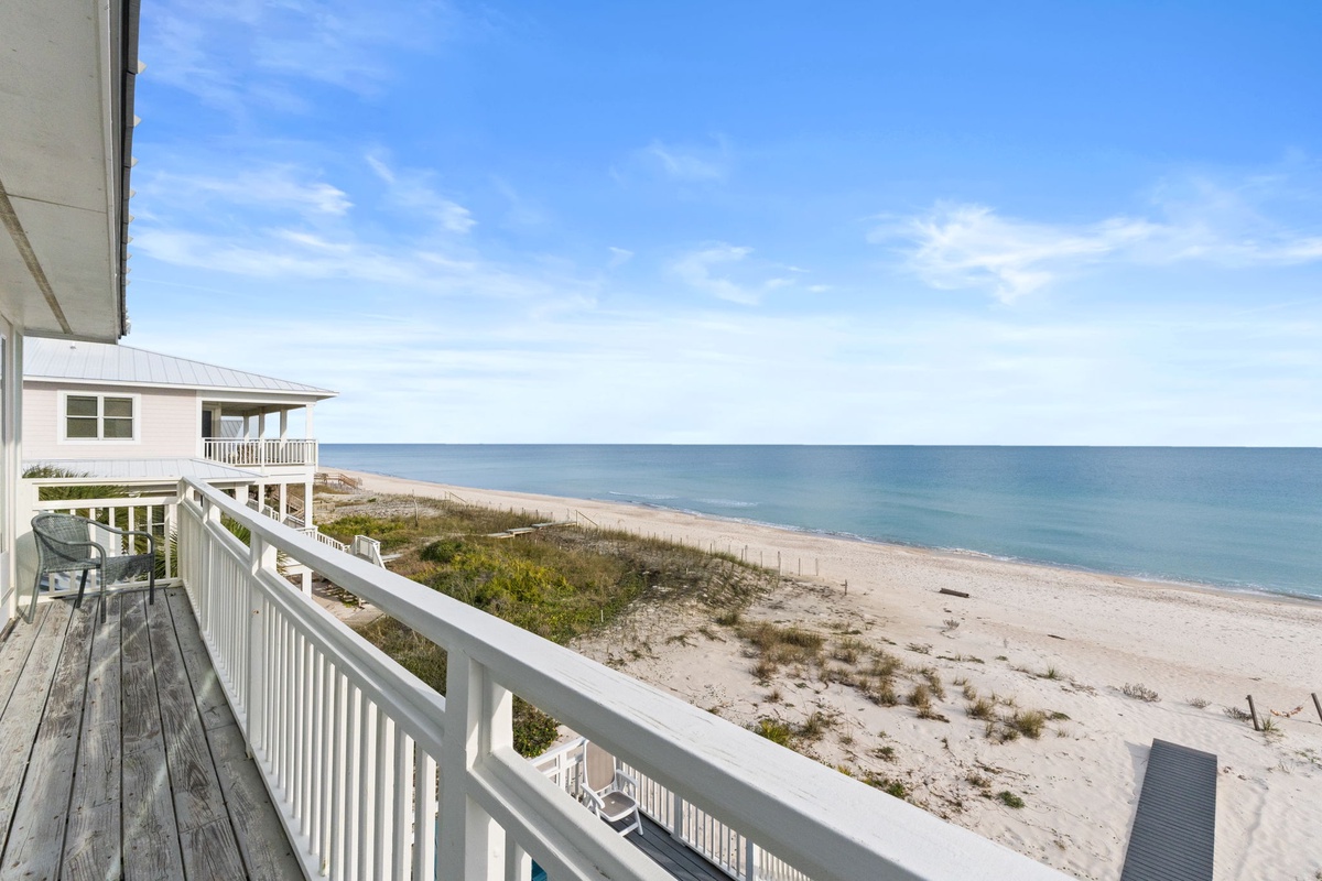 Pristine beachfront stretches endlessly from this elevated deck, offering unobstructed ocean views and direct beach access.