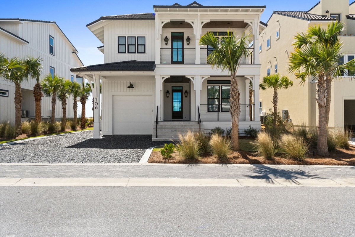 Elegant two-story home with coastal charm, featuring tropical palm landscaping and convenient garage parking in a well-maintained neighborhood.