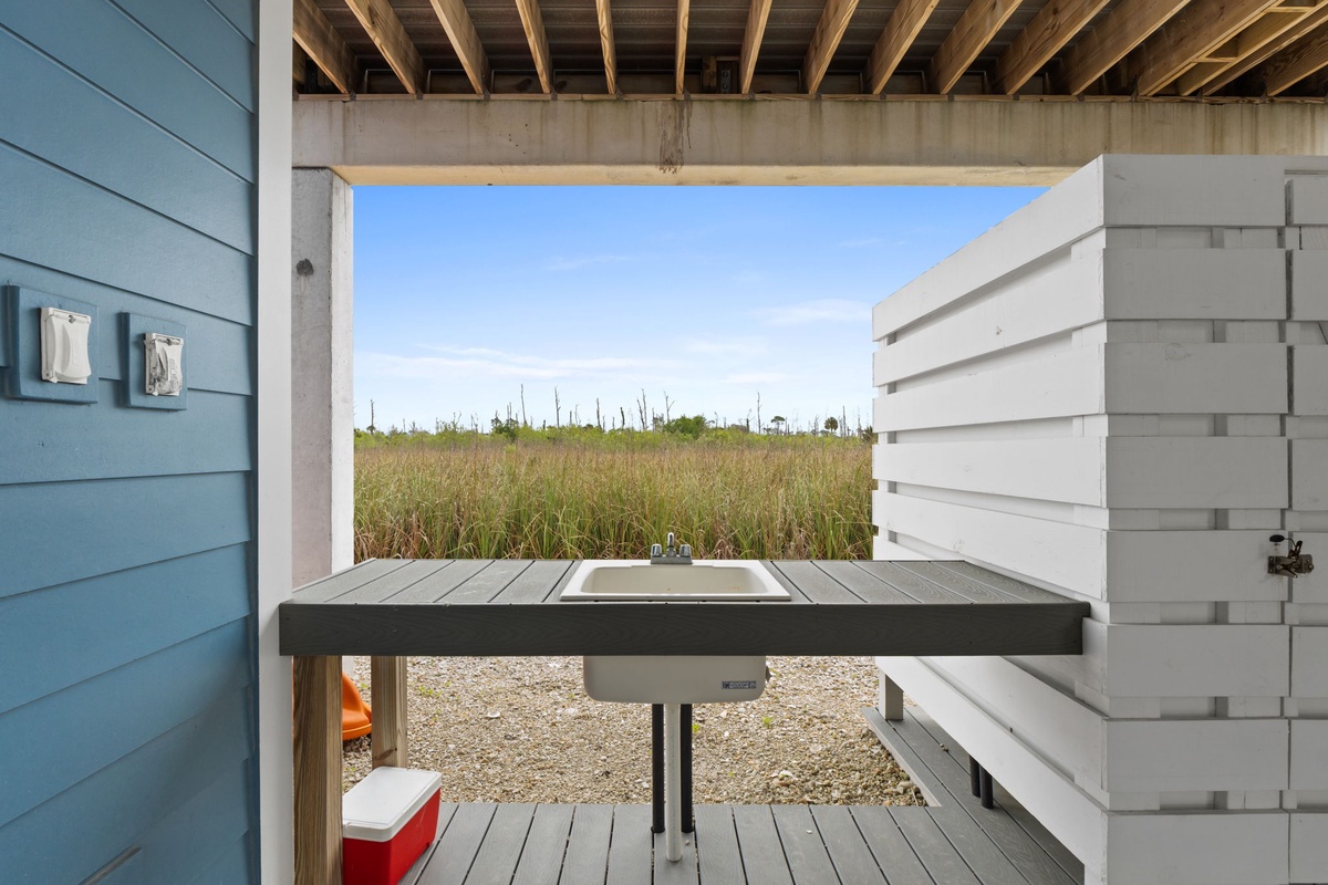 Rinse off after beach adventures at your private outdoor sink, framed by natural grasslands and endless sky.