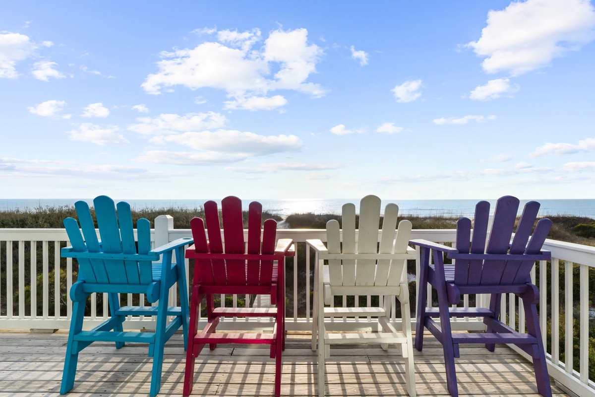 Relax in colorful Adirondack chairs while enjoying stunning ocean views from your private deck—the perfect spot for morning coffee.