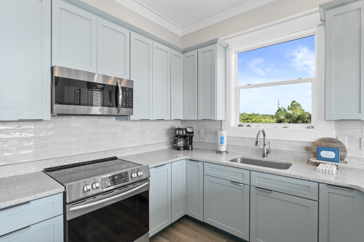 Prepare your favorite meals in this bright, modern kitchen with stainless steel appliances, elegant gray cabinets, and natural light streaming through the window.