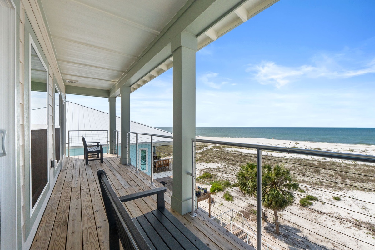A covered balcony with ocean views offers a peaceful spot to relax and watch the waves roll in. Comfortable seating invites you to unwind while enjoying the coastal breeze.