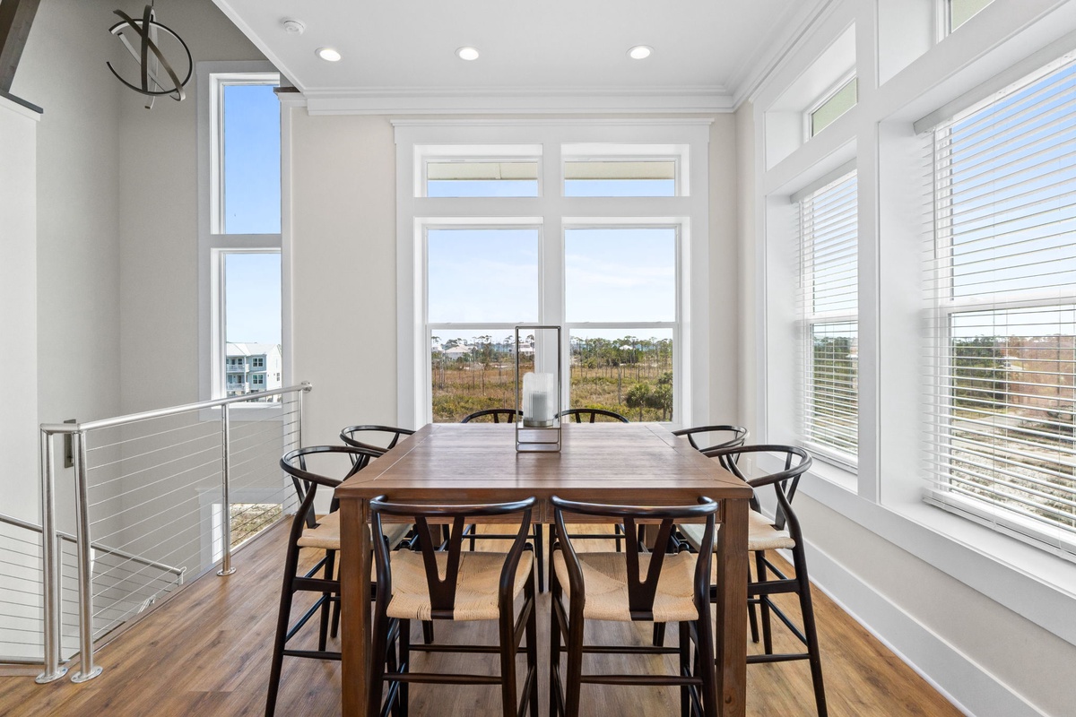 Gather around this beautiful wooden dining table where natural light floods through expansive windows, creating the perfect setting for your memorable meals together.