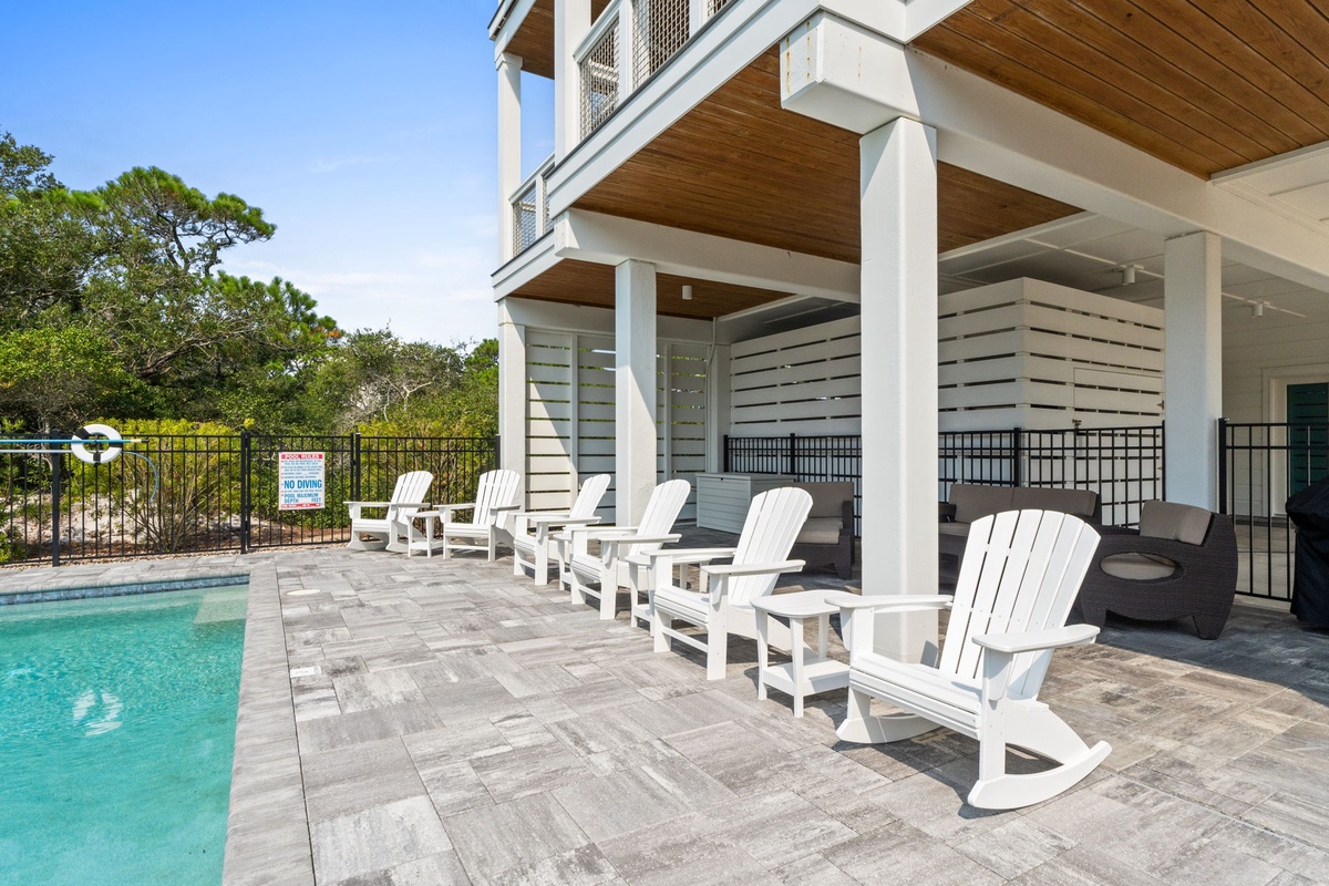 Sink into a white rocking chair on your private poolside patio, where warm wood ceilings and cool tile floors create the perfect spot to unwind with a refreshing drink in hand.