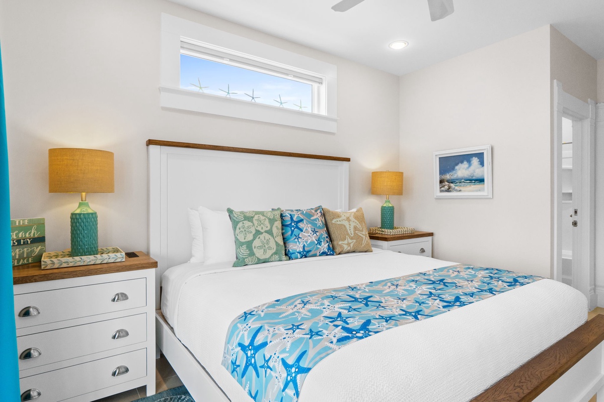 Drift off in your serene bedroom featuring coastal touches, warm wood accents, and soft natural light streaming through the window above your comfortable bed.