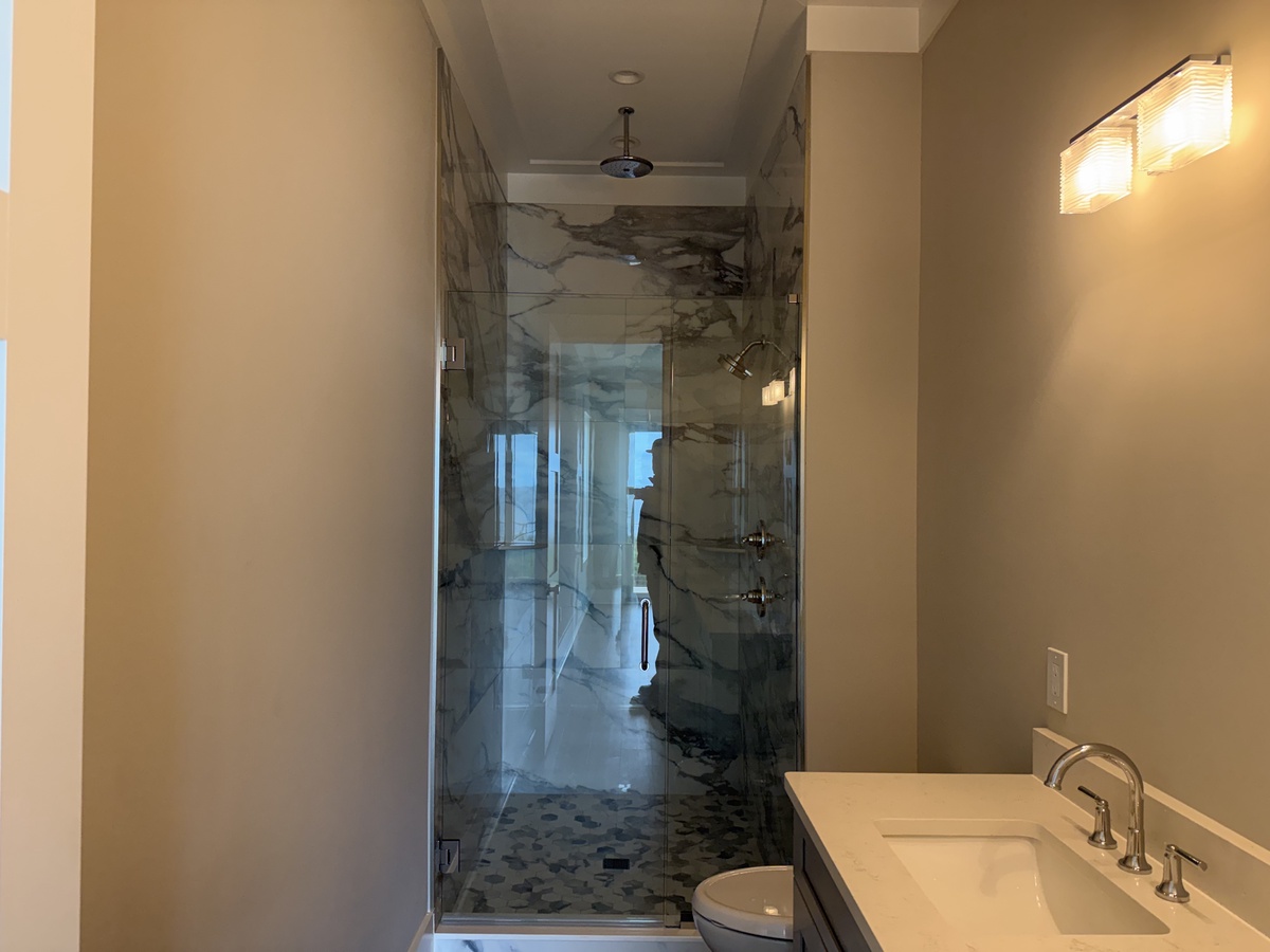 Indulge in your private spa-like bathroom featuring stunning marble walls and a luxurious glass-enclosed shower for the ultimate relaxation.