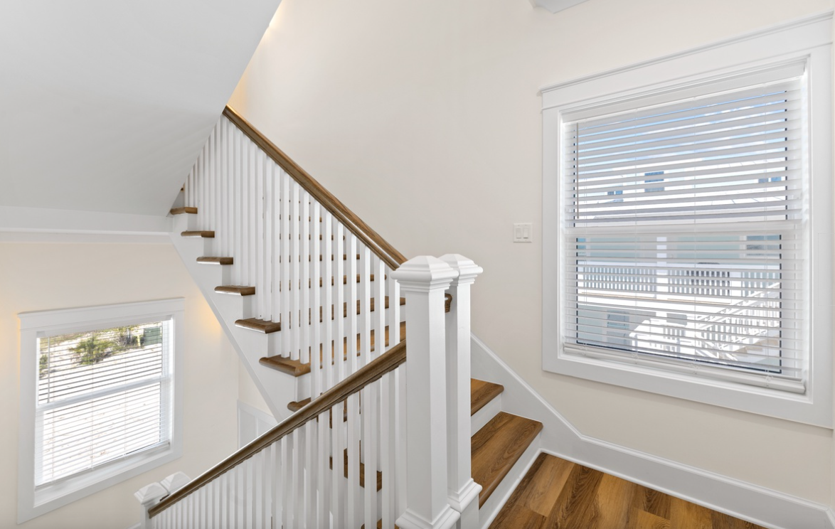 Step up to your upstairs retreat via this elegant stairway, where warm wood floors and bright windows create an inviting path to comfort.