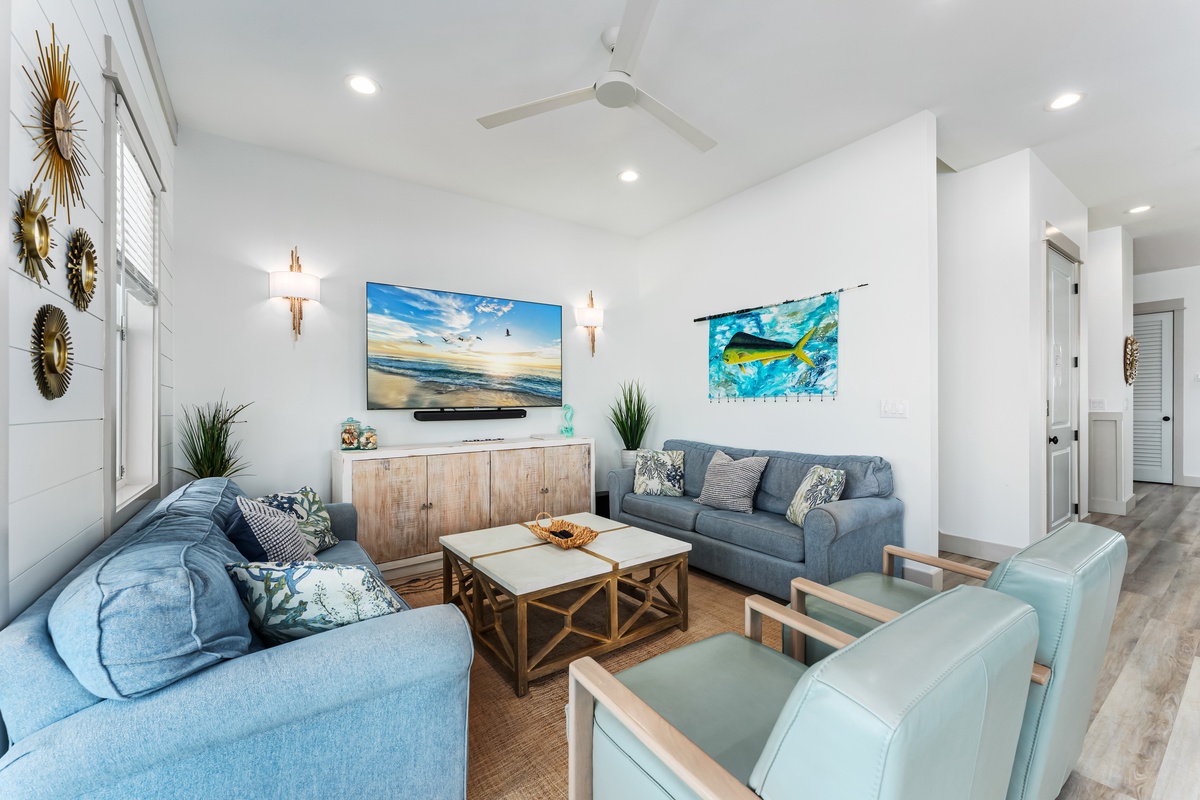 Unwind in your coastal-inspired living space with ocean artwork, cozy seating, and modern amenities for perfect relaxation.
