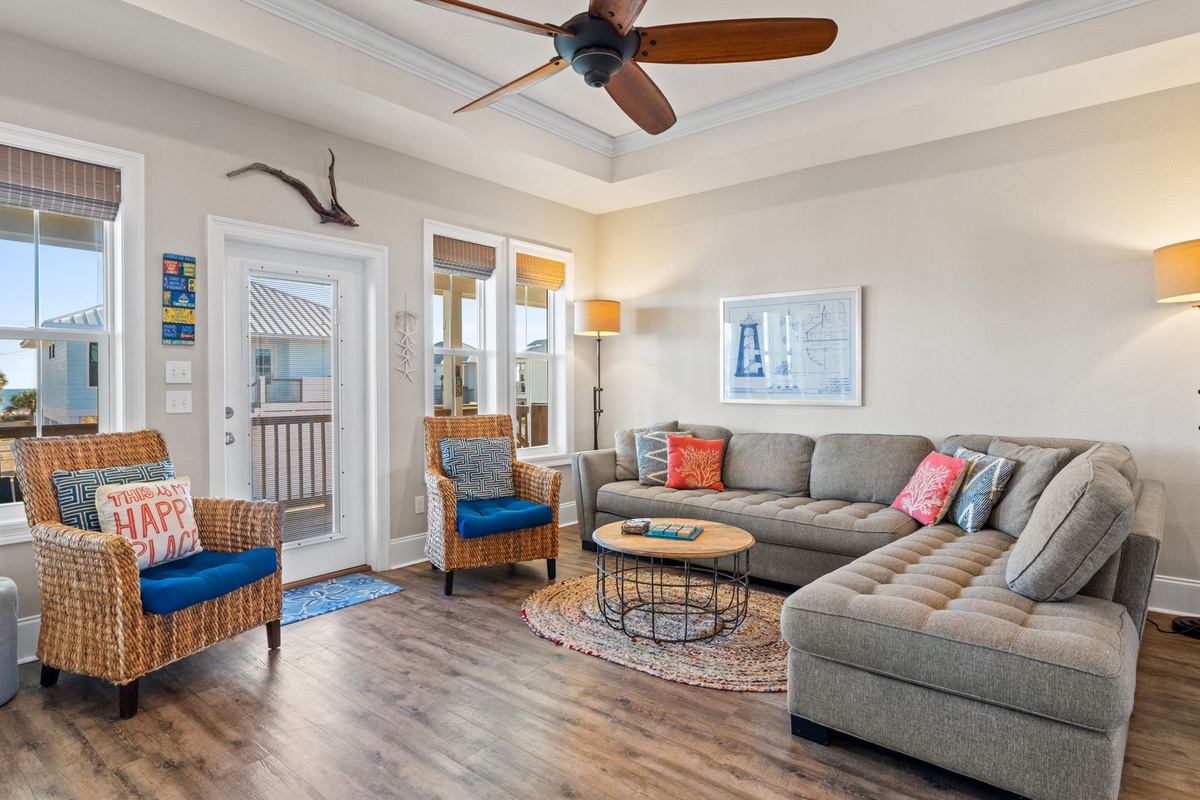 Relax in your spacious living room with comfortable sectional seating, coastal charm, and ceiling fan keeping you cool.