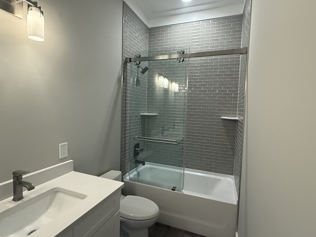 Step into your sleek, modern bathroom featuring contemporary gray subway tile and a luxurious glass-enclosed tub-shower combo for your ultimate relaxation.