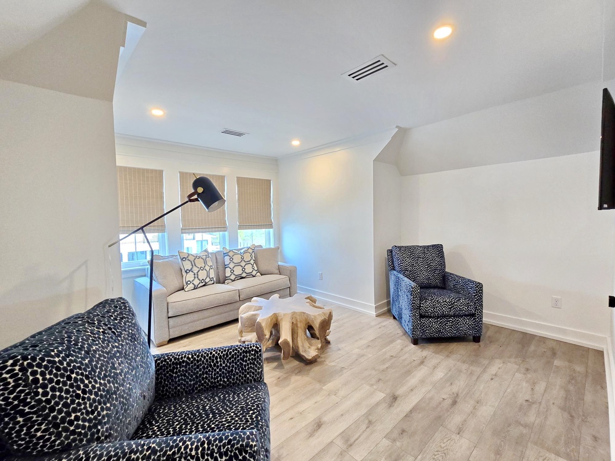 Sink into plush seating and unwind in your stylish living space, featuring designer furniture and natural light streaming through bamboo blinds.