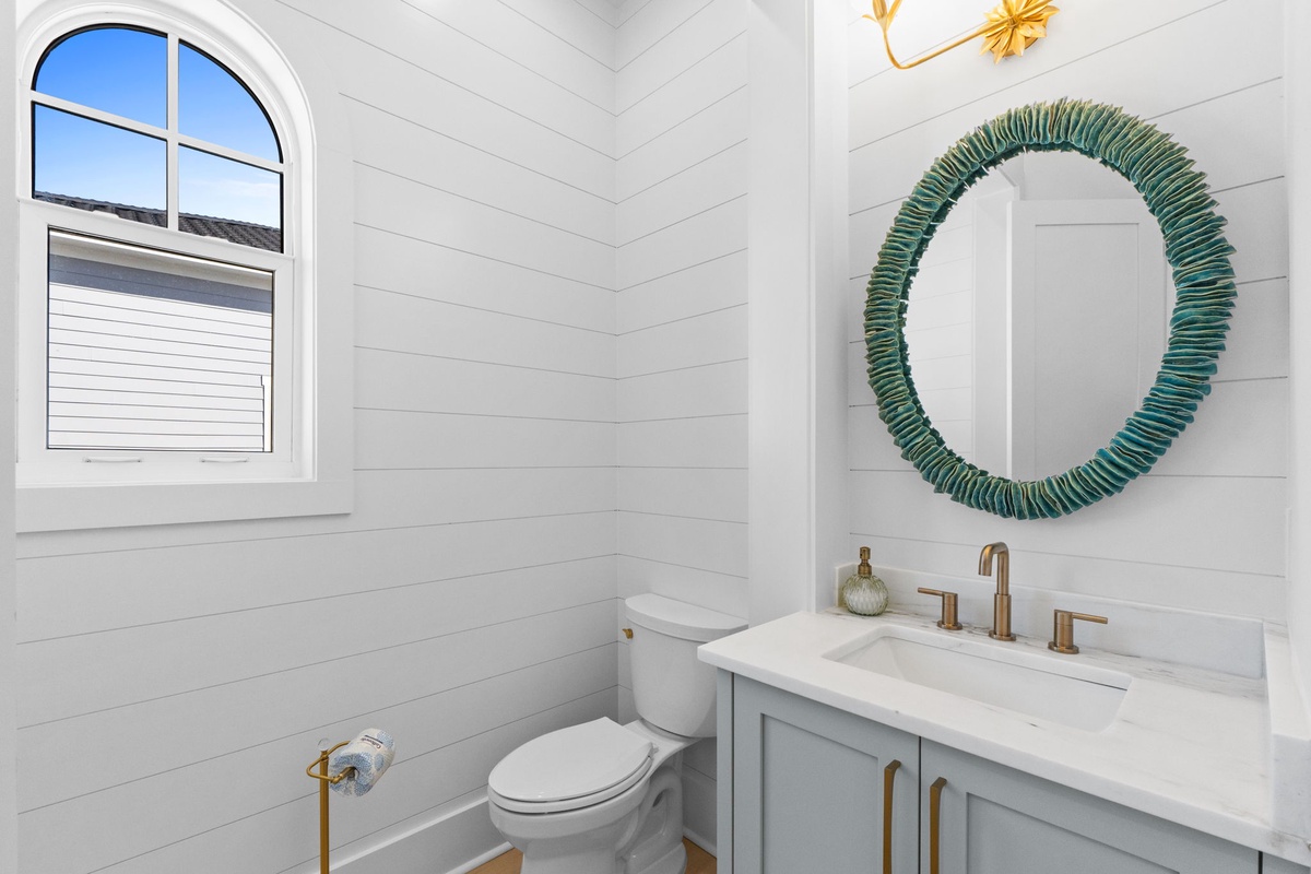 Step into your stylish powder room with shiplap walls, marble vanity, and charming coastal mirror that perfectly frames your morning routine.