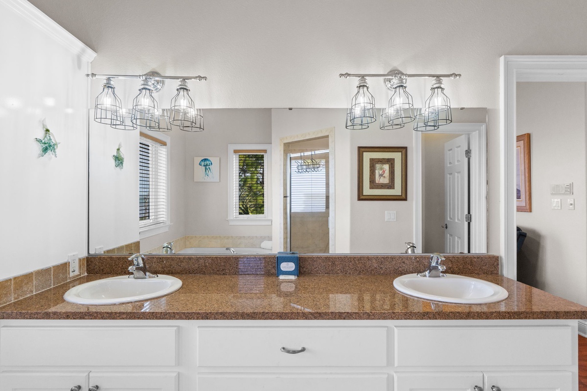 Start your morning routine in this bright double-vanity bathroom with stylish lighting and granite countertops.