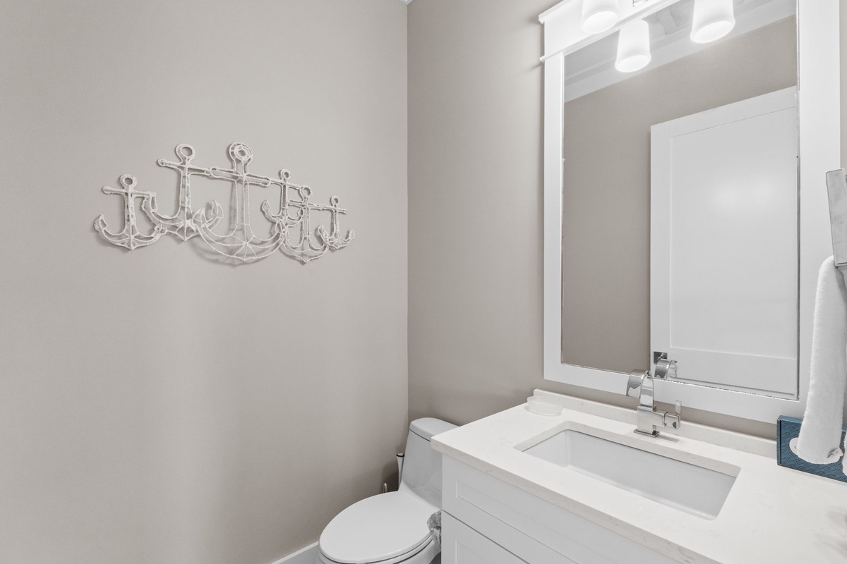 Freshen up in this coastal-inspired powder room, where crisp white fixtures and nautical anchor hooks blend beachy charm with modern comfort.