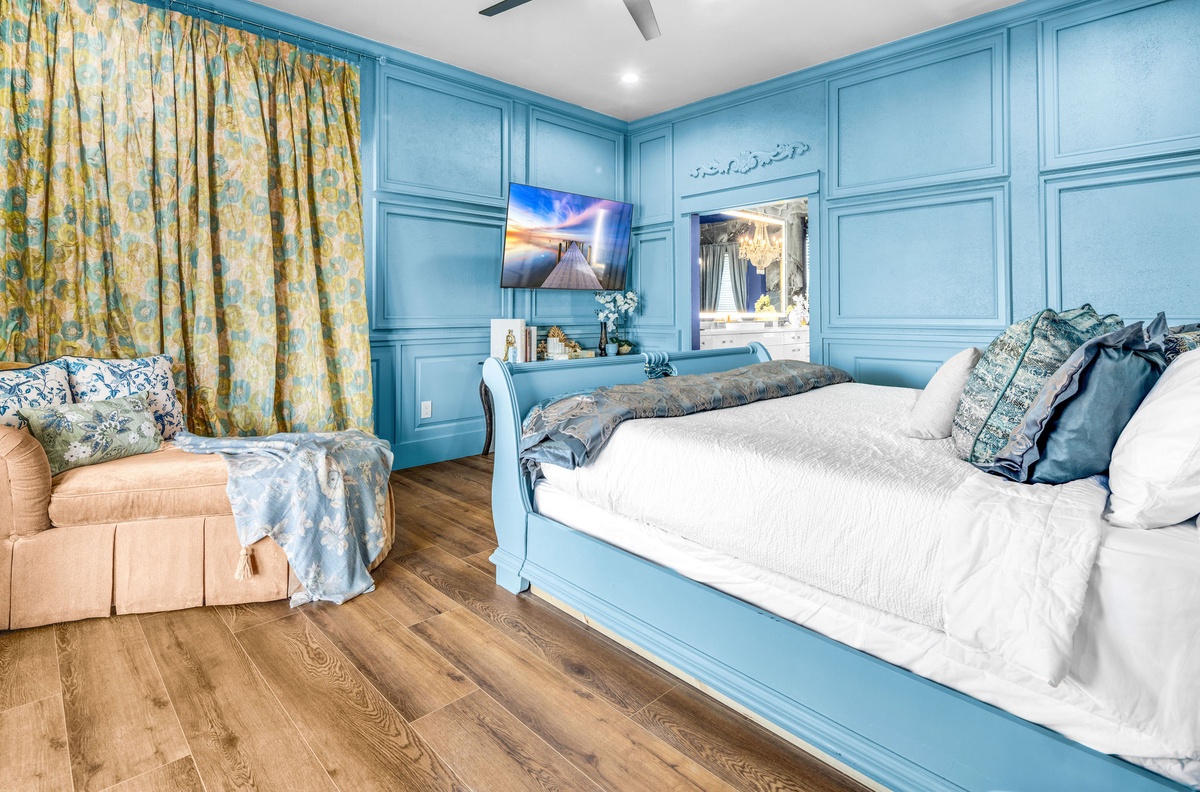 Unwind in your coastal-inspired bedroom featuring elegant blue millwork, plush seating, and modern entertainment for your perfect retreat.