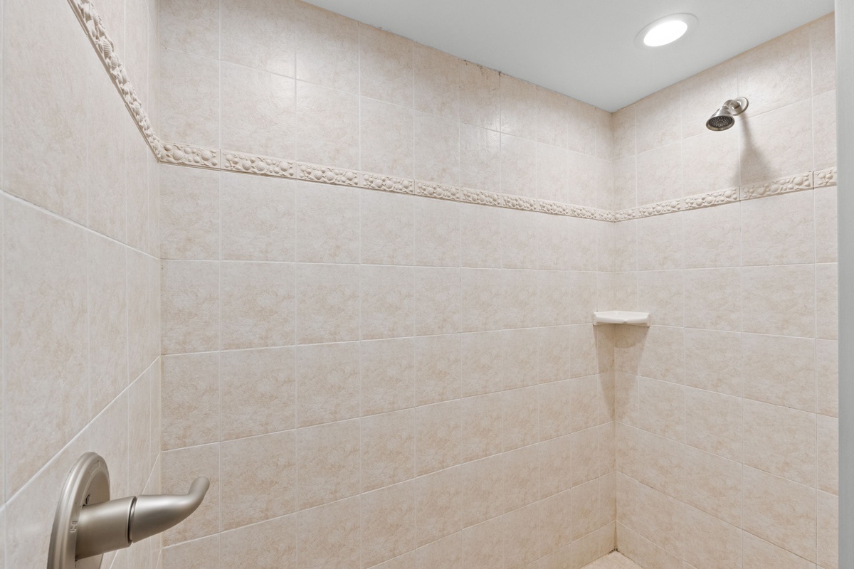 Spacious walk-in shower with elegant tiled walls and rainfall showerhead—perfect for refreshing after a day exploring the area.
