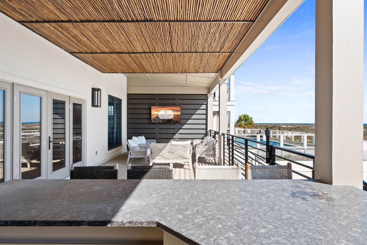 Unwind on your private covered terrace with comfortable seating, bamboo ceiling details, and stunning views of the surrounding area.