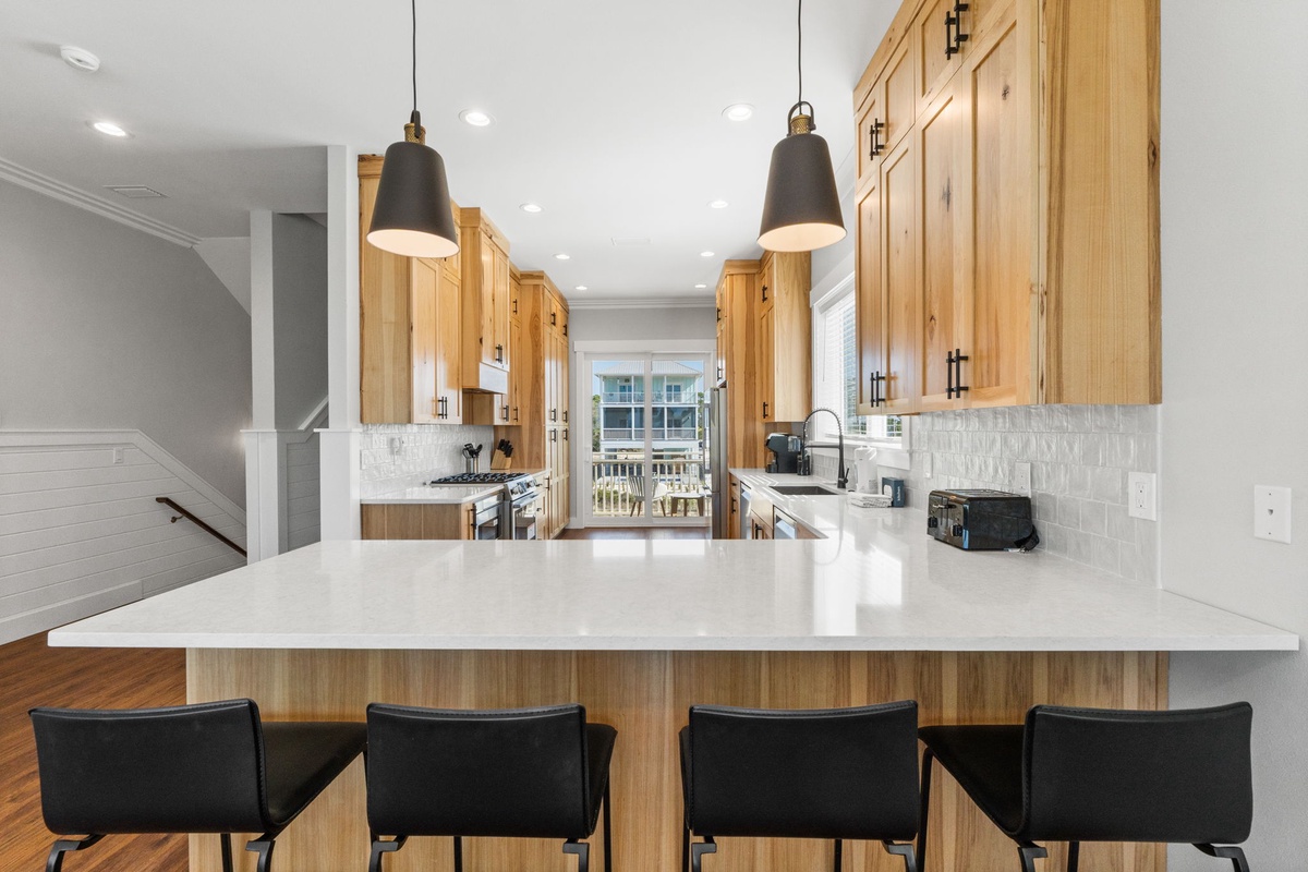 Your gourmet kitchen features warm wood cabinets, pristine quartz counters, and a spacious island perfect for morning coffee or evening meal prep.